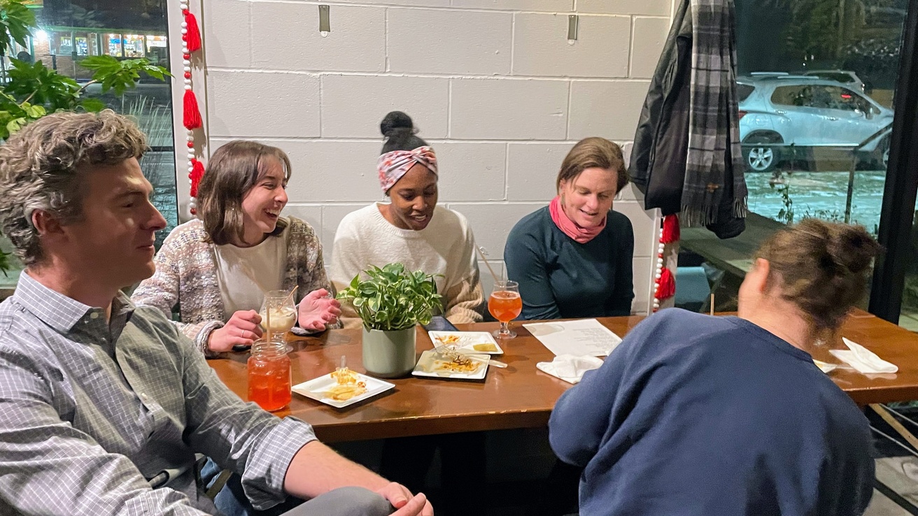 Image of graduate students and BBIP faculty sitting around a table in a cozy setting. Drinks and some light food are sitting on the table.